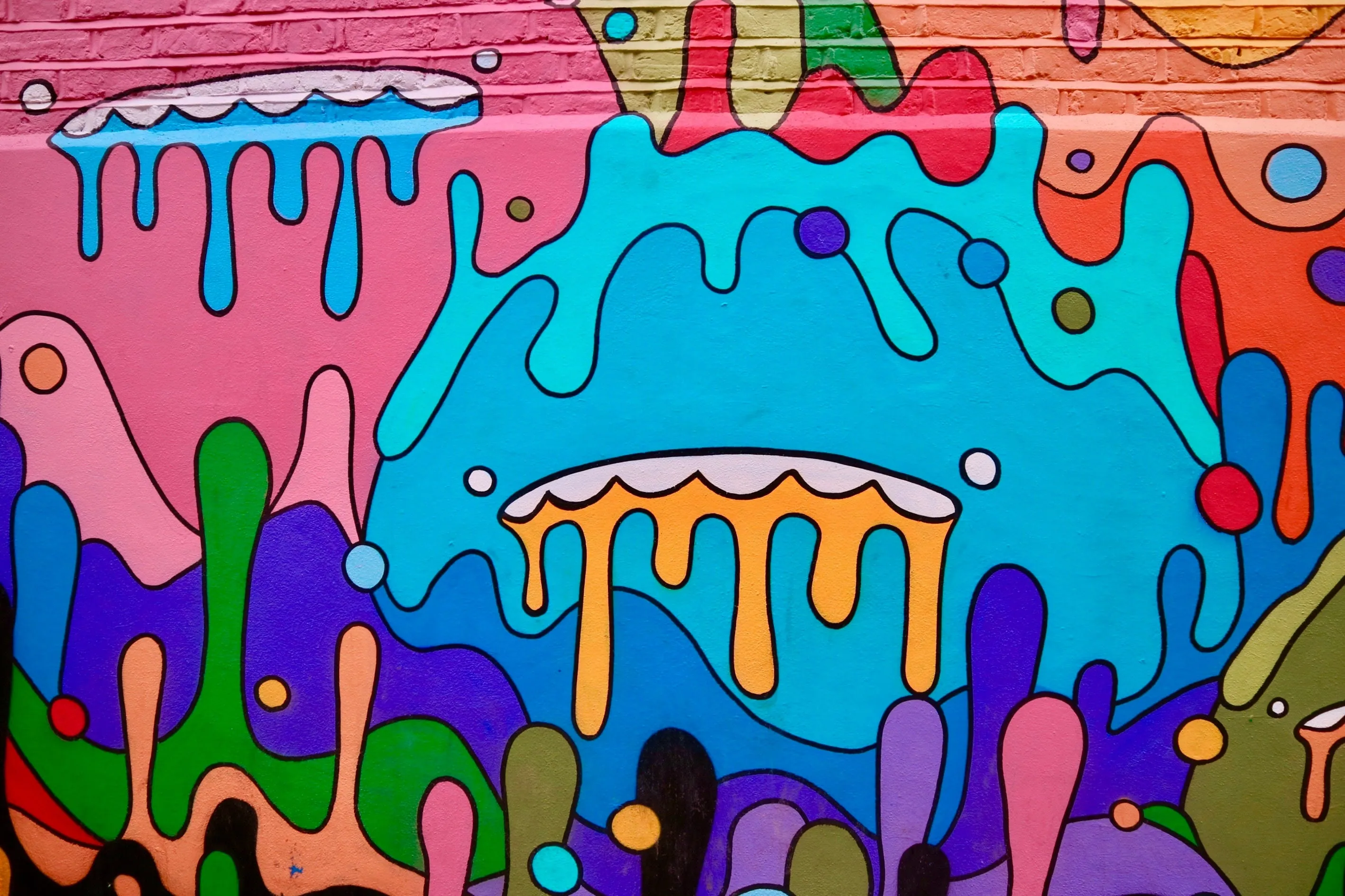 A colourful mural of dripping paint shapes in blue, pink, orange and green