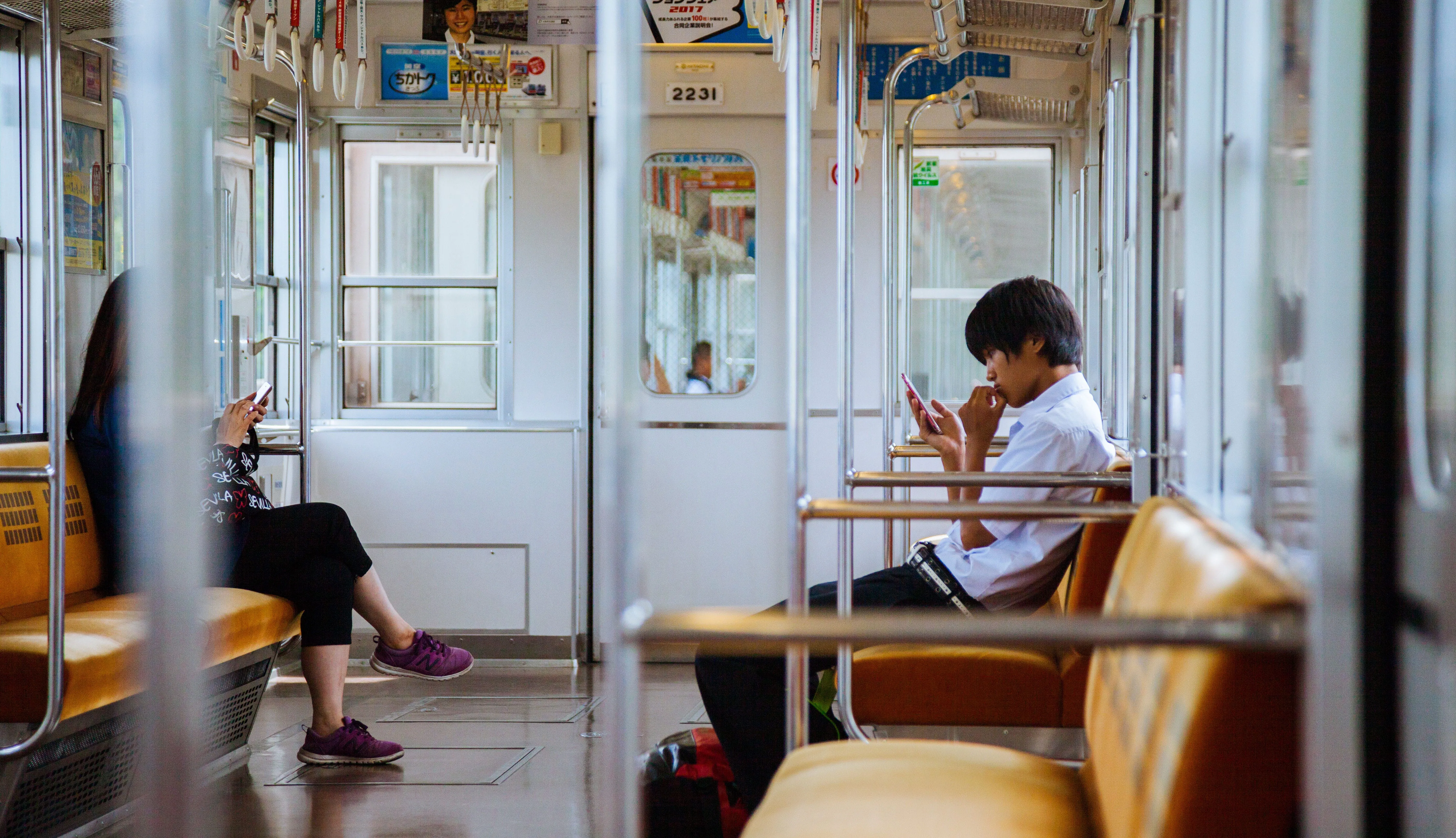 Two people looking at their phones on a quiet subway carriage