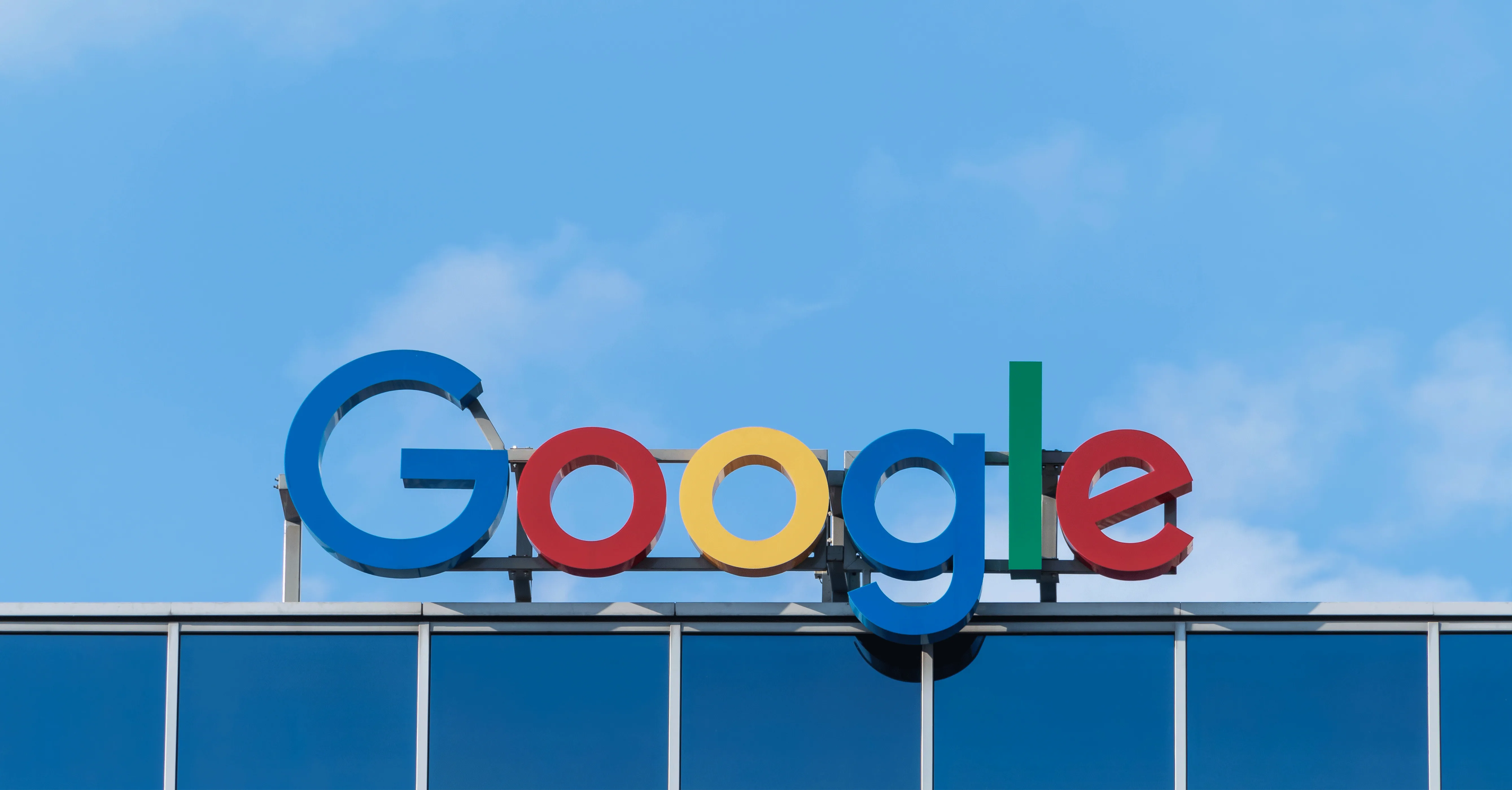 The Google sign on top of an office building against a blue sky