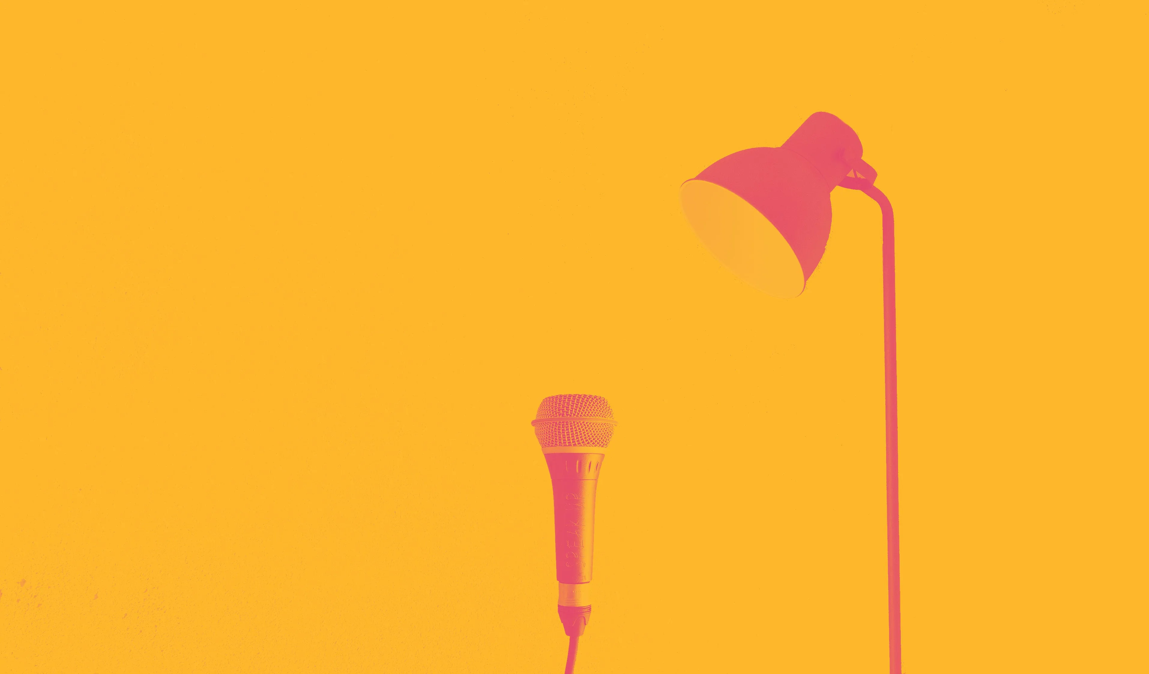 A microphone under a desk lamp, in red on yellow
