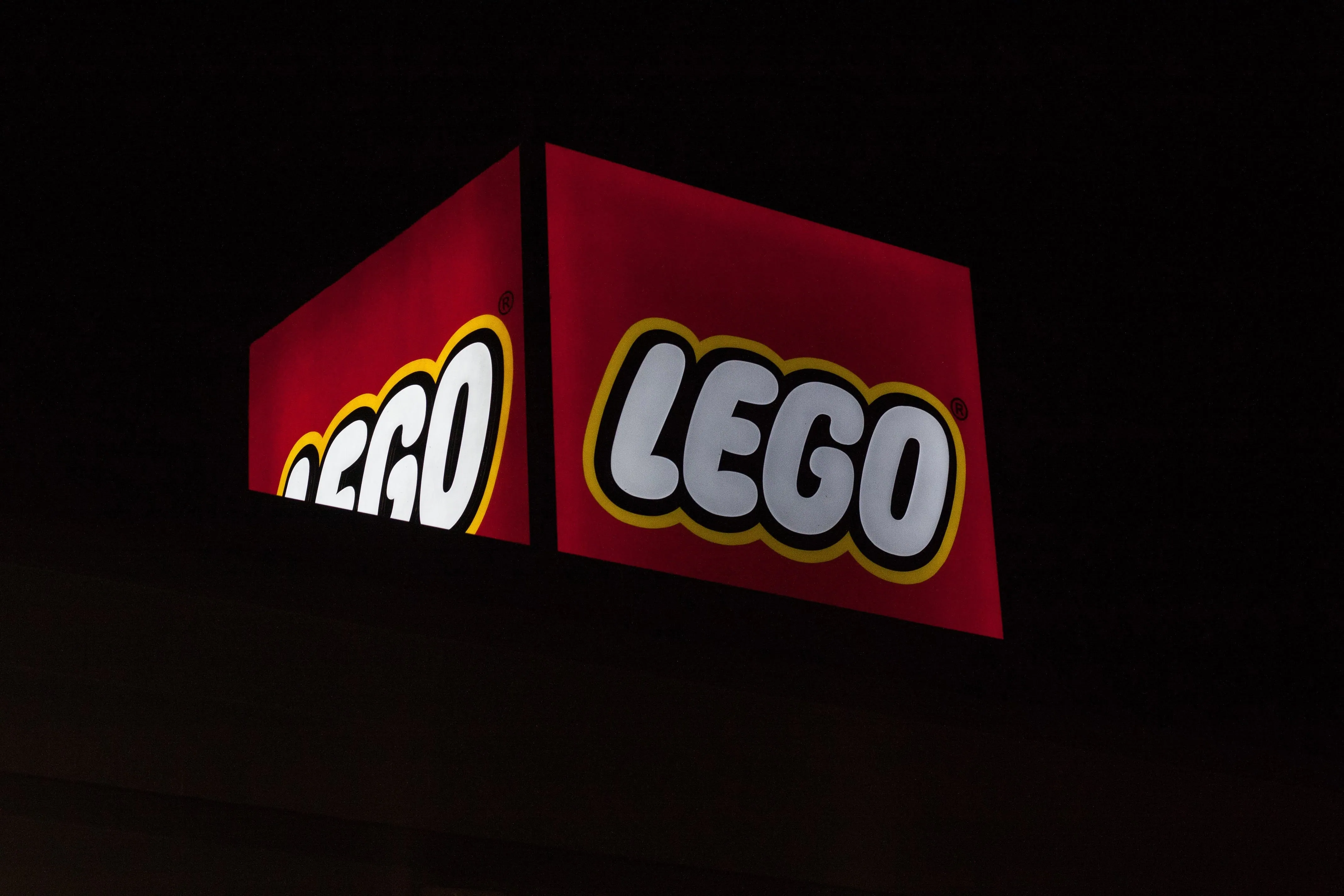 The LEGO logo lit up on a dark shop sign