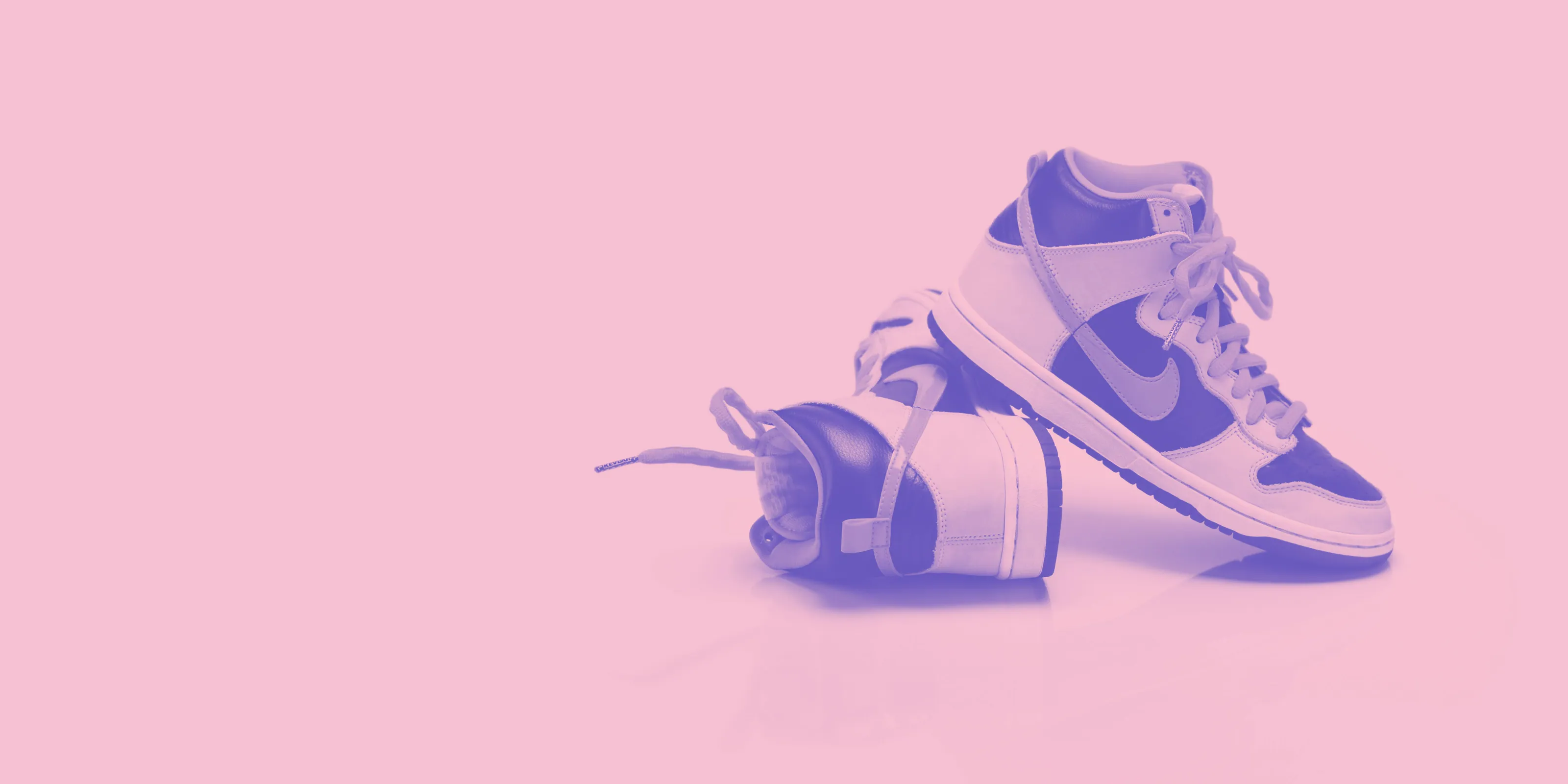 A pair of Nike Dunk trainers with a weight beside them, tinted violet on pink